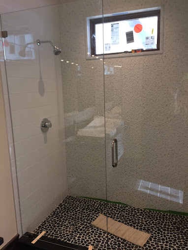glass door shower with black stone flooring