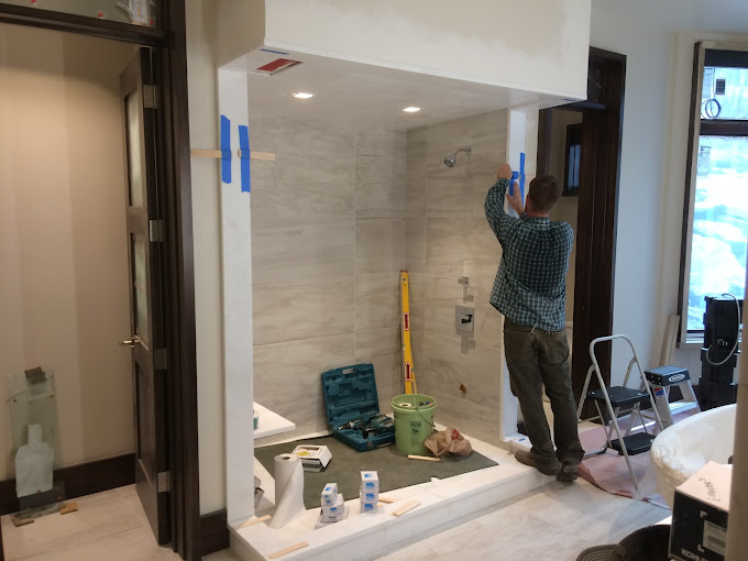 man taping side of shower under construction